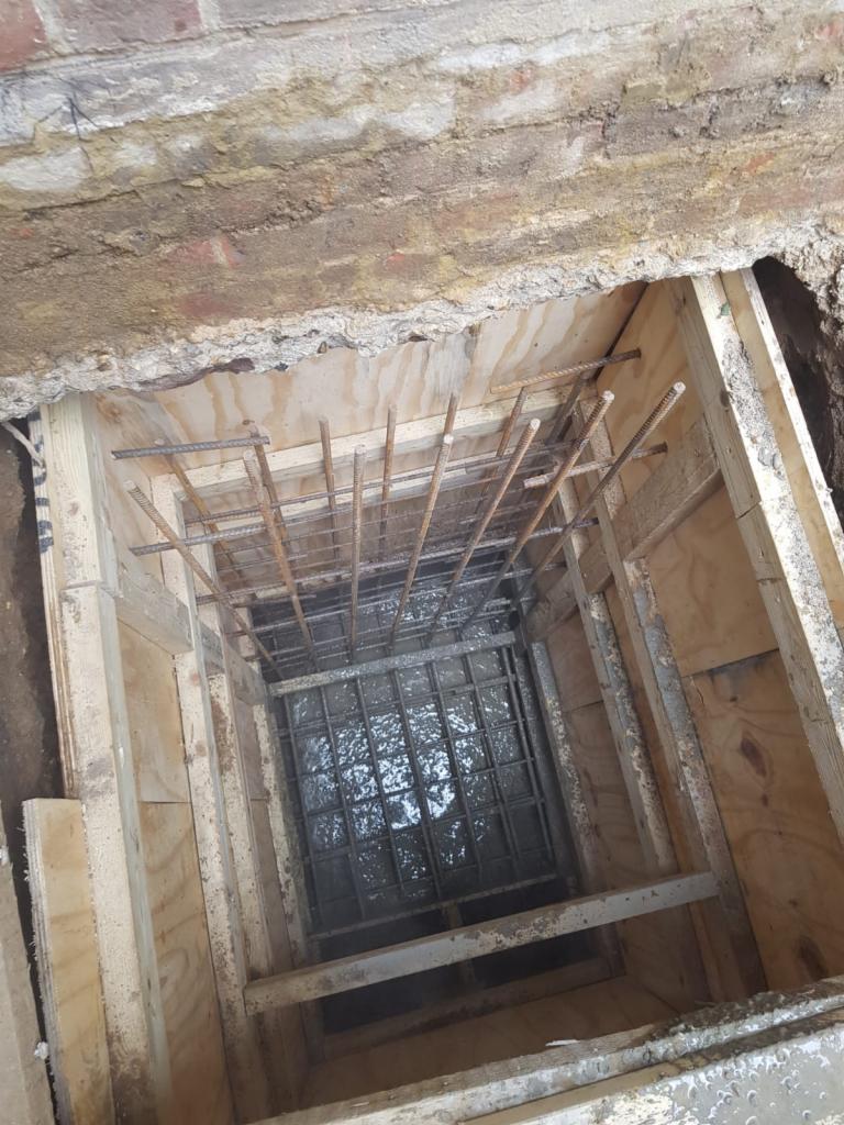 Wykop z drewnianym szalunkiem i zbrojeniem przed zalaniem betonem, widok z góry.