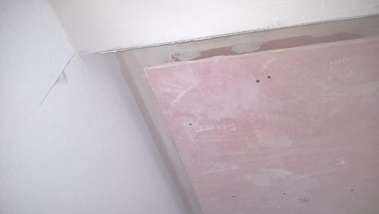 Fragment ściany i sufitu z widocznym łączeniem płyt gipsowo-kartonowych, w trakcie prac wykończeniowych, z widocznymi śladami szpachli.