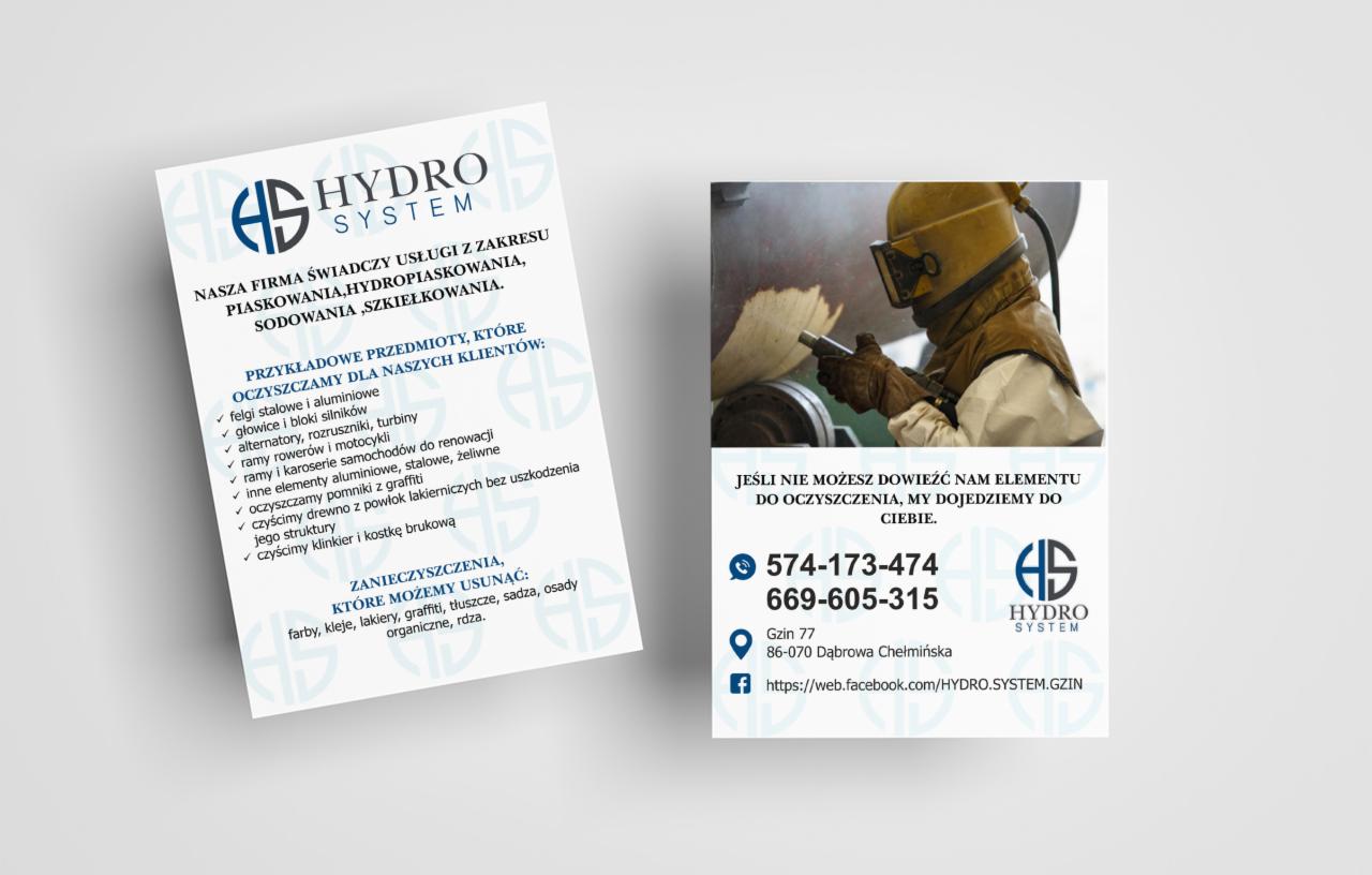 Pracownik w kombinezonie ochronnym i masce piaskuje metalowy element w warsztacie, w tle ulotka reklamowa firmy Hydro System oferującej piaskowanie, hydropiaskowanie, sodowanie i szkiełkowanie.