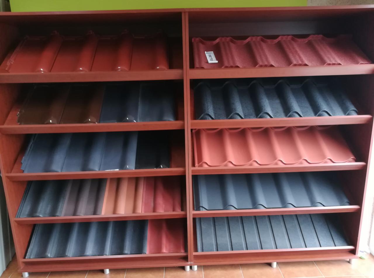 Ekspozycja różnych kolorów i wzorów metalowych pokryć dachowych na drewnianym regale w sklepie.