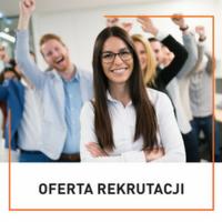 Uśmiechnięta kobieta w okularach na pierwszym planie, za nią grupa entuzjastycznie nastawionych osób z podniesionymi rękami w tle, sugerująca sukces rekrutacyjny.