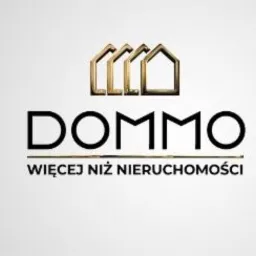 Logo firmy DOMMO z trzema złotymi symbolami domu powyżej nazwy i hasłem 'WIĘCEJ NIŻ NIERUCHOMOŚCI' poniżej.