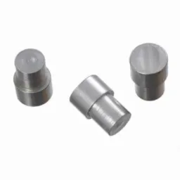 Trzy metalowe elementy o cylindrycznym kształcie z przewężeniem pośrodku, ułożone na białym tle. Jeden element leży poziomo, dwa stoją pionowo.