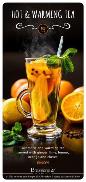 Szklanka parującej herbaty z imbirem, limonką, cytryną, pomarańczą i goździkami, udekorowana miętą, na tle owoców i ciemnego drewna, promowana przez Brasserie 27.