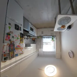 Jasna kuchnia z białymi frontami, ozdobiona rysunkami dzieci na lodówce, z widokiem na okno z roletami i wiszącym kwiatem, oświetlona lampą sufitową.