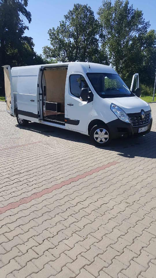 Biały Renault Master z otwartymi drzwiami bocznymi i tylnymi, zaparkowany na kostce brukowej z widocznym wnętrzem części ładunkowej.