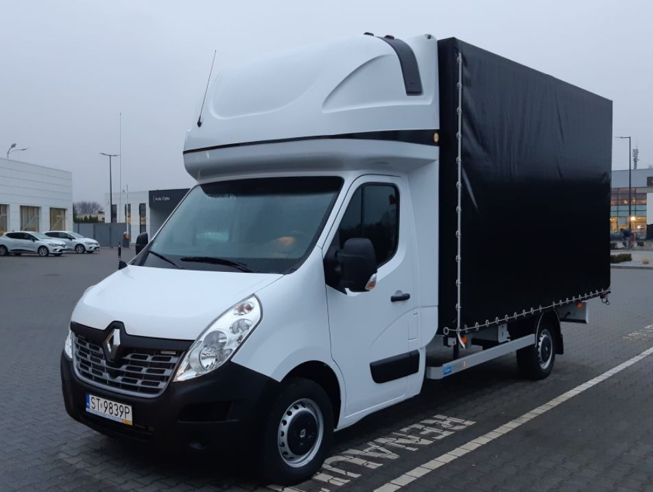 Biały Renault Master z plandeką, zaparkowany na parkingu, widoczny z boku, z numerem rejestracyjnym ST-9839P.