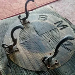 Drewniany wieszak na ubrania z logo BMW, wykonany z postarzanego drewna i metalowych haczyków w stylu retro.