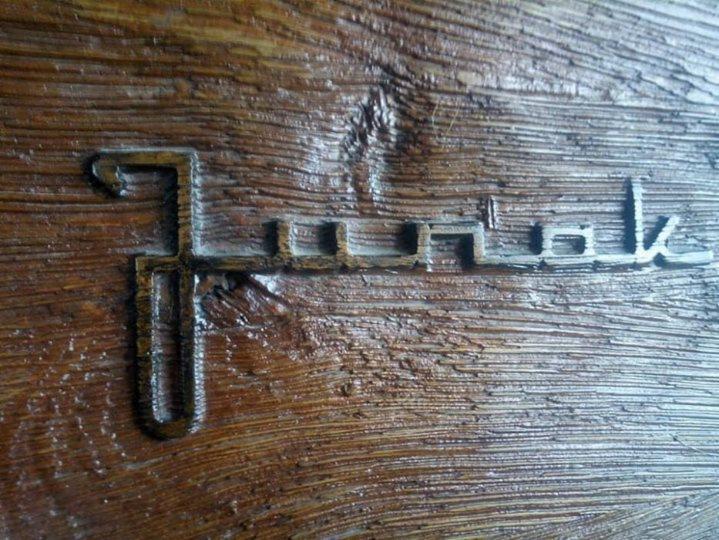 Szczegółowe ujęcie wyrytego napisu 'Juriak' na teksturowanej, brązowej powierzchni drewnopodobnej.