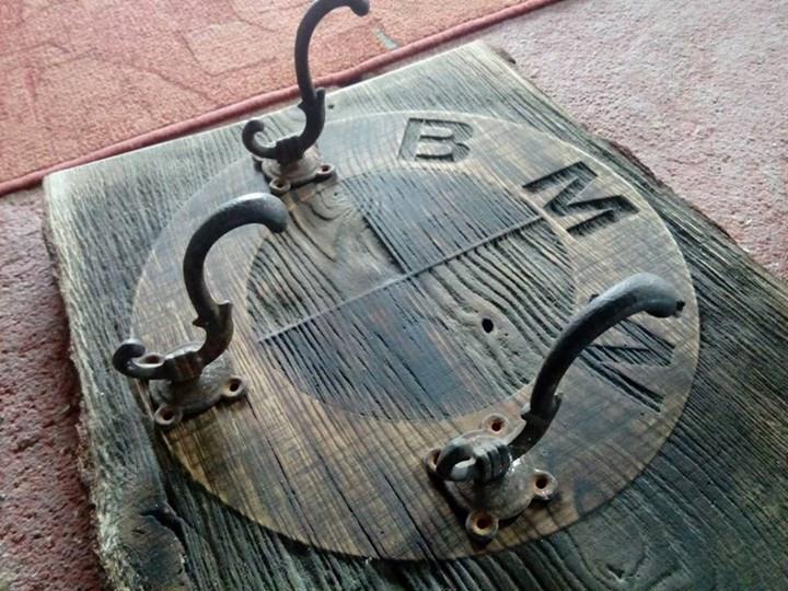 Drewniany wieszak na ubrania z logo BMW, wykonany z postarzanego drewna i metalowych haczyków w stylu retro.