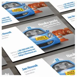 Wizytówki szkoły nauki jazdy z ilustracją niebieskiego samochodu z literą 'L' na dachu i pomarańczowymi pachołkami w tle.