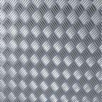 Metalowa powierzchnia z regularnym wzorem rombów, każdy z nich wypełniony drobnymi, równoległymi prążkami, tworząc efekt antypoślizgowy.