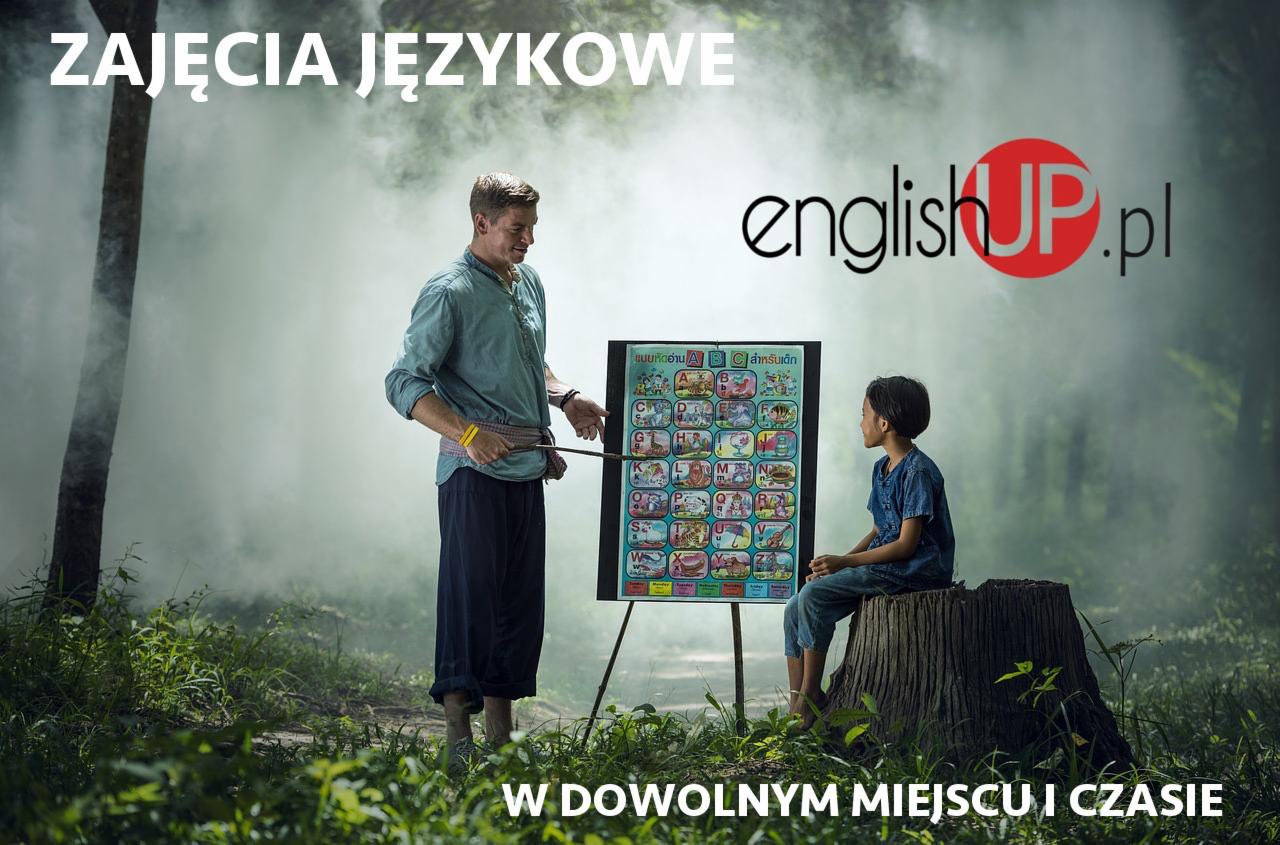 Nauczyciel z drewnianym wskaźnikiem uczy dziewczynkę alfabetu na tle leśnej scenerii, z widocznym logo englishUP.pl