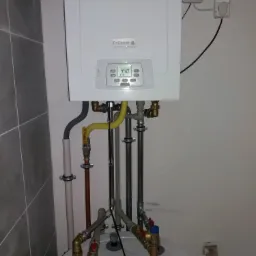 Kocioł gazowy kondensacyjny De Dietrich, model Lumea MPX 24/SR100, zamontowany na zbiorniku c.w.u., z widocznymi przyłączami gazowymi i wodnymi, oraz panelem sterowania wskazującym temperaturę 44.0...