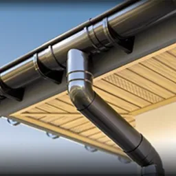 Ciemne orynnowanie z rurą spustową zamontowane pod okapem z drewnianą boazerią, widok z dołu pod kątem.