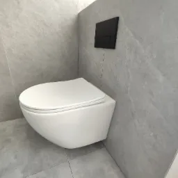 Świeżo zamontowana podwieszana toaleta z czarnym panelem spłukującym na tle szarych płytek imitujących kamień, w tle widoczna wiertarka.