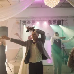 Zespół muzyczny w trakcie występu na weselu, wokalista z mikrofonem w ręku, oświetlenie sceniczne