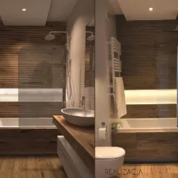 Wizualizacja i zdjęcie z realizacji: Łazienka z drewnianą okładziną, podświetlaną wnęką nad wanną, owalną umywalką na drewnianym blacie. Po lewej stronie 'Projekt', po prawej 'Realizacja'.