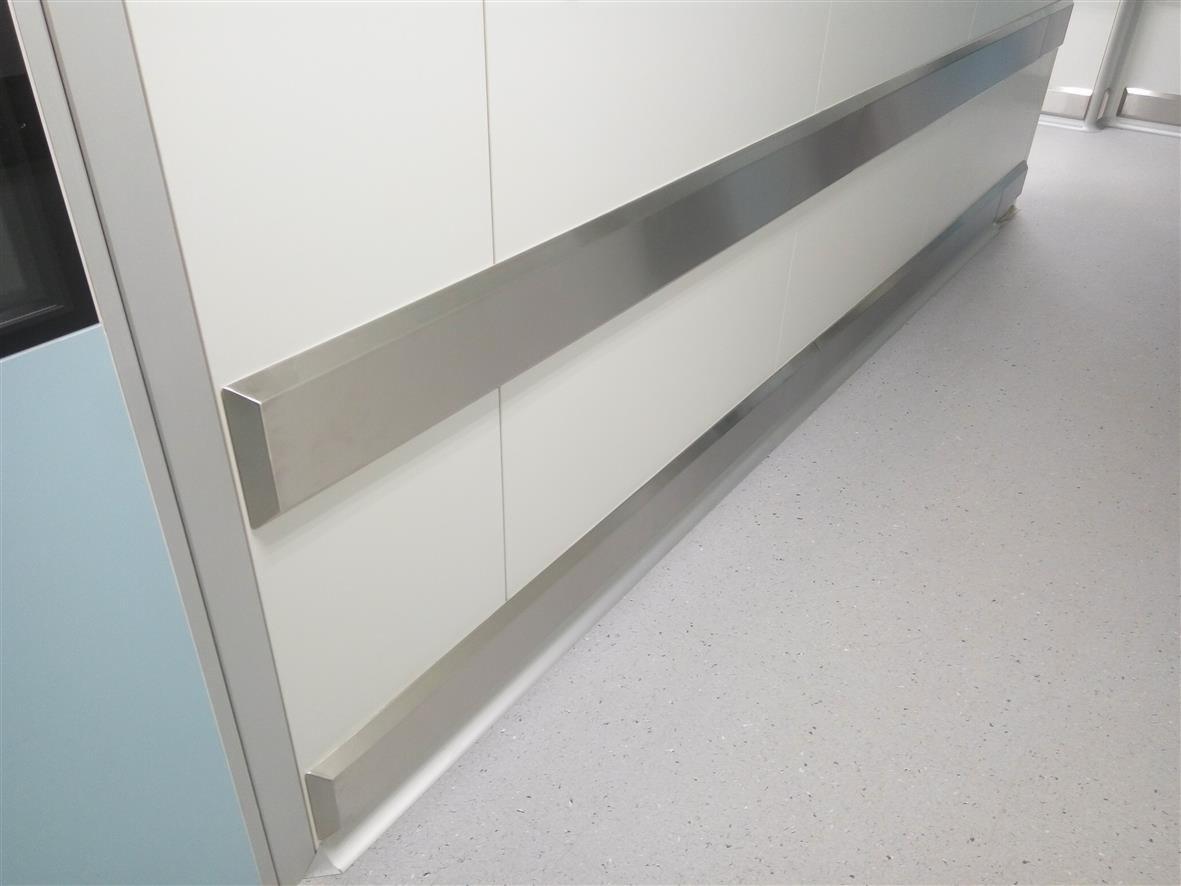 Szczegółowe ujęcie szpitalnego korytarza z białymi panelami ściennymi i dwoma równoległymi, prostokątnymi poręczami ze stali nierdzewnej, zamontowanymi na różnych wysokościach, chroniącymi ściany...