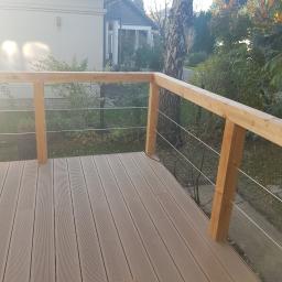 EWA WARDAK - Nowoczesny taras kompozytowy z drewnianą balustradą i stalowymi linkami w Pruszkowie, widok z perspektywy użytkownika.