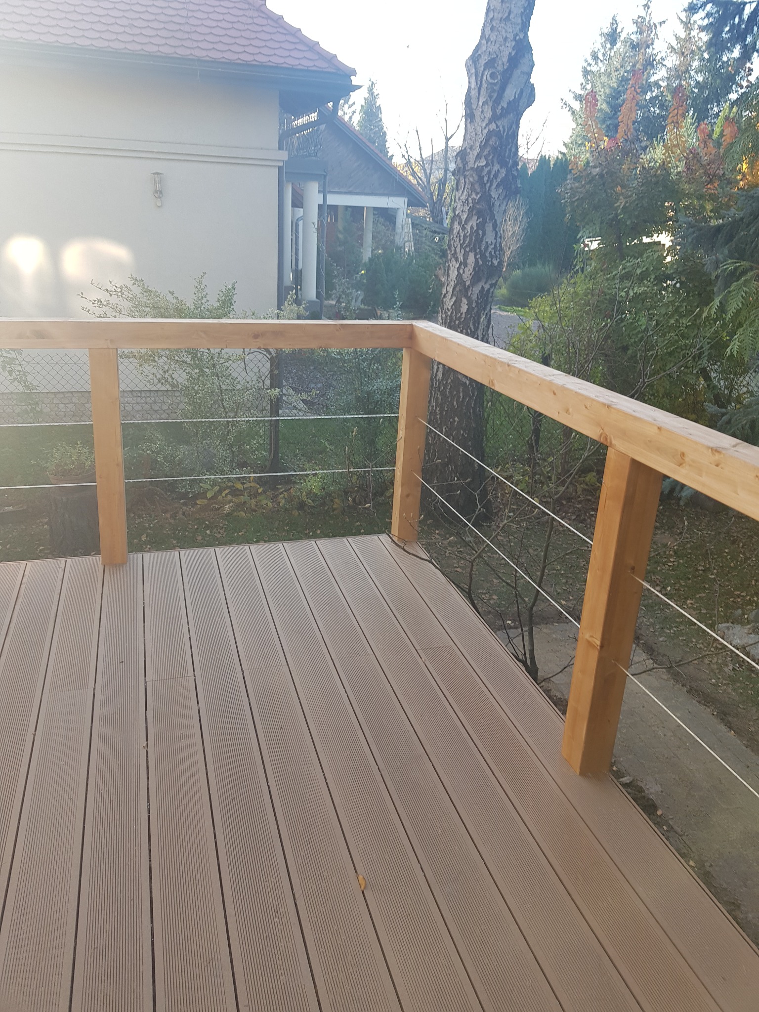 Nowoczesny taras kompozytowy z drewnianą balustradą i stalowymi linkami w Pruszkowie, widok z perspektywy użytkownika.