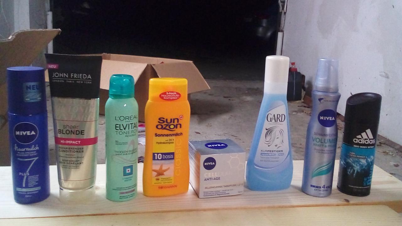 Różnorodny zestaw kosmetyków i środków higieny osobistej różnych marek, w tym Nivea i L'Oreal, zgrupowany na drewnianej powierzchni w Gdowie, z pudełkiem kartonowym w tle.