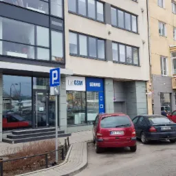 Fasada budynku z szyldem 'LabGSM Serwis' nad wejściem; zaparkowane samochody przed lokalem.