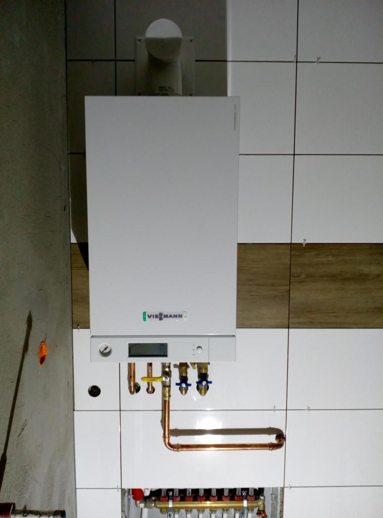 Nowy, biały piec gazowy marki Viessmann zamontowany na płytkach w łazience w Siedlcu, z widocznymi miedzianymi rurami i zaworami.