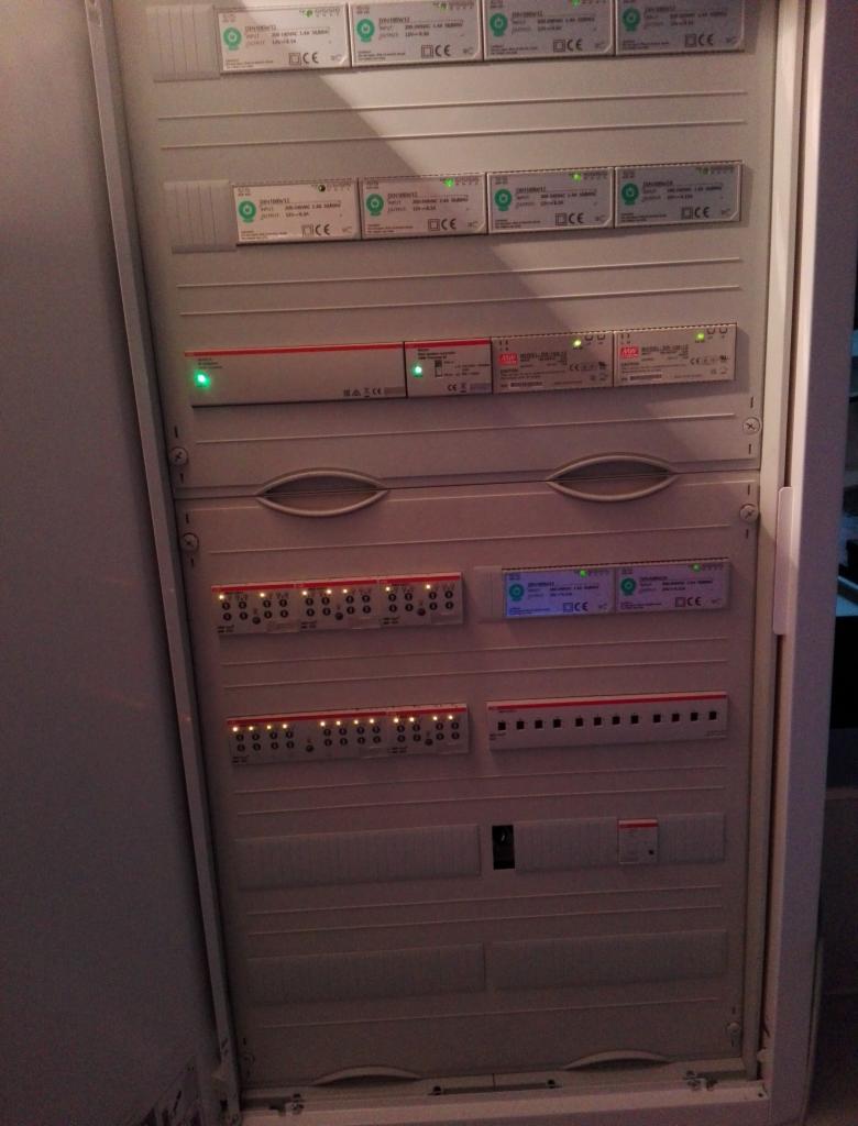 Rozdzielnica elektryczna z widocznymi modułami zabezpieczeń i sygnalizacją LED, zamontowana w obudowie wnękowej, oświetlona z góry.