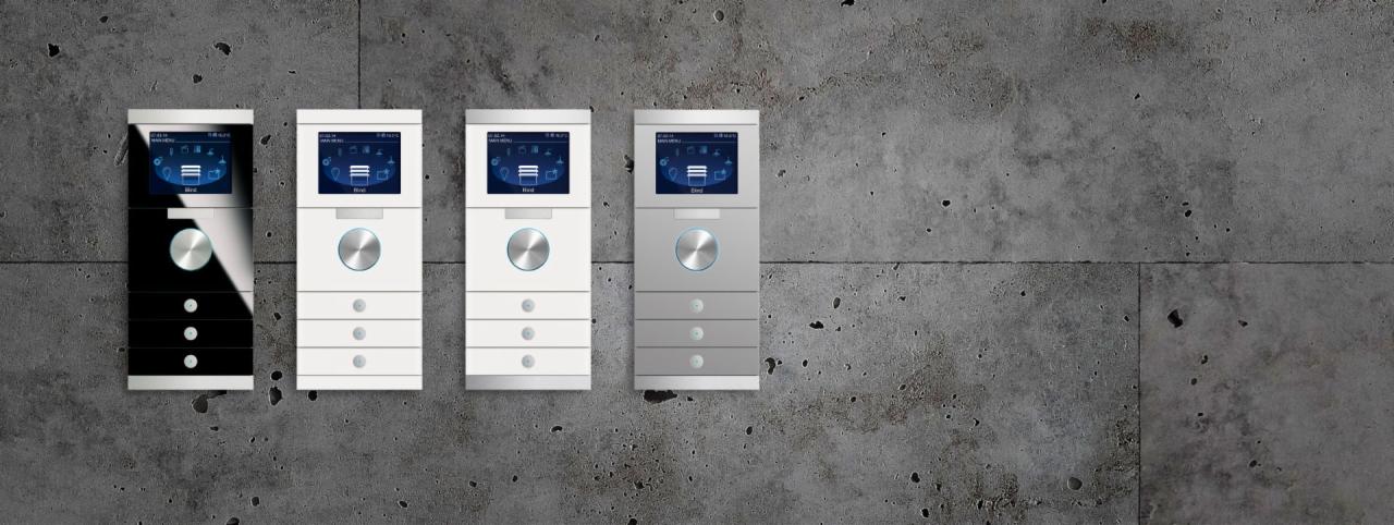 Cztery panele sterowania systemem inteligentnego domu w kolorach czarnym, białym i szarym, zamontowane na tle surowego betonu.