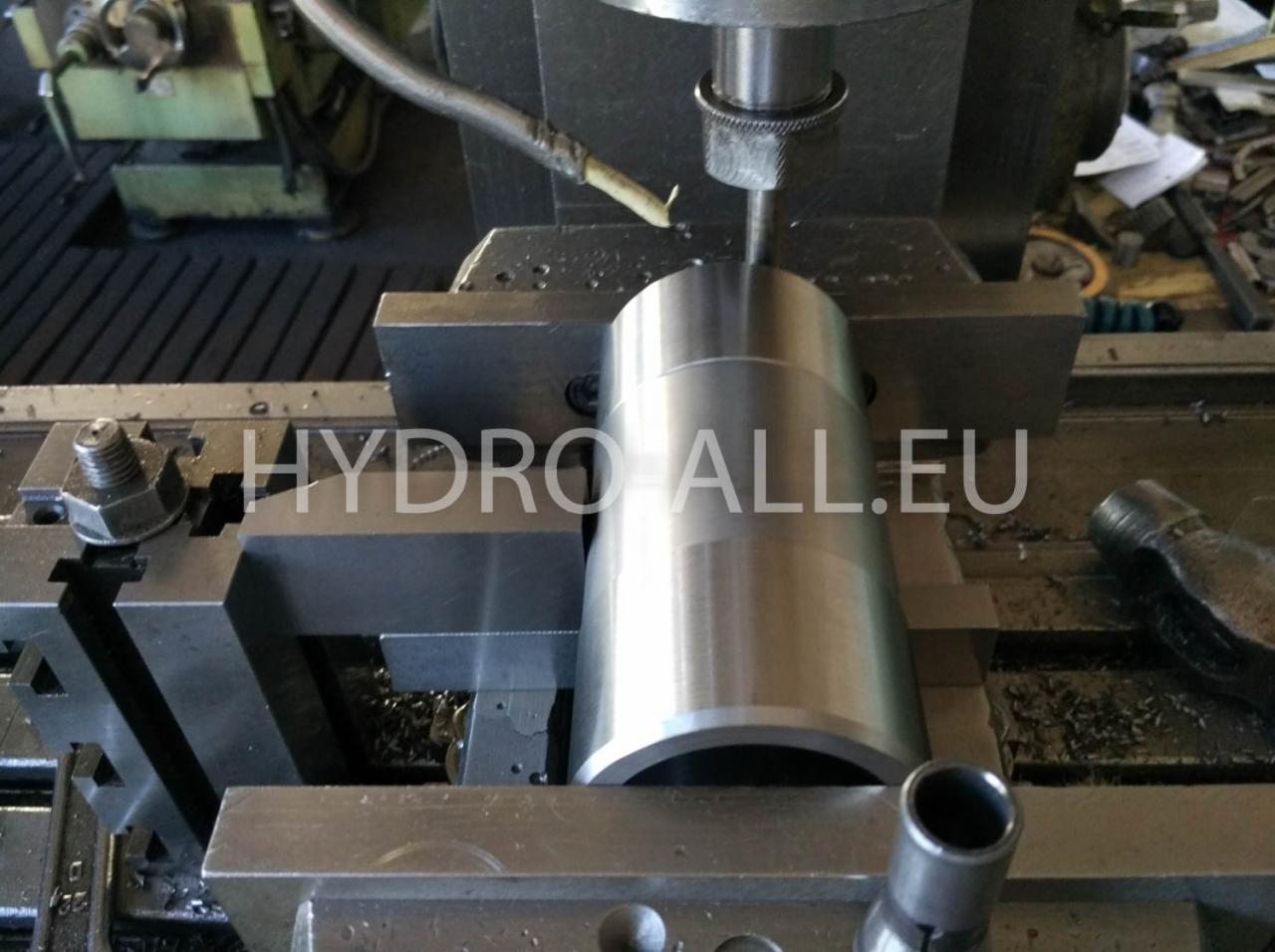 Metalowy element obrabiany na tokarce z użyciem chłodziwa, widoczne wióry i uchwyt tokarski.