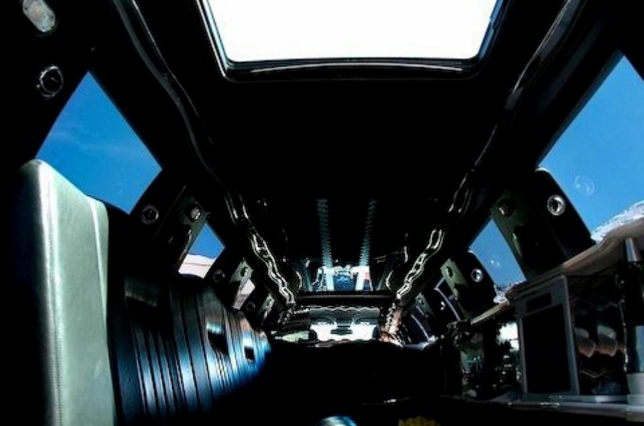 Wnętrze luksusowej limuzyny z oknem dachowym, widok z tyłu kabiny na przednią szybę, skórzane siedzenia i elementy oświetlenia.