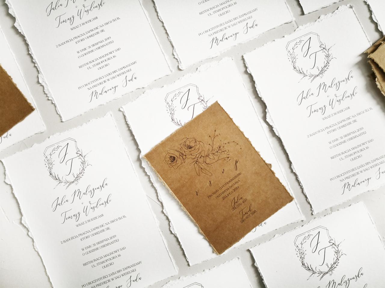 Eleganckie zaproszenia ślubne z ręcznie rwanym brzegiem, w odcieniach bieli i brązu, z motywami roślinnymi i kaligrafią, ułożone na jasnym tle.