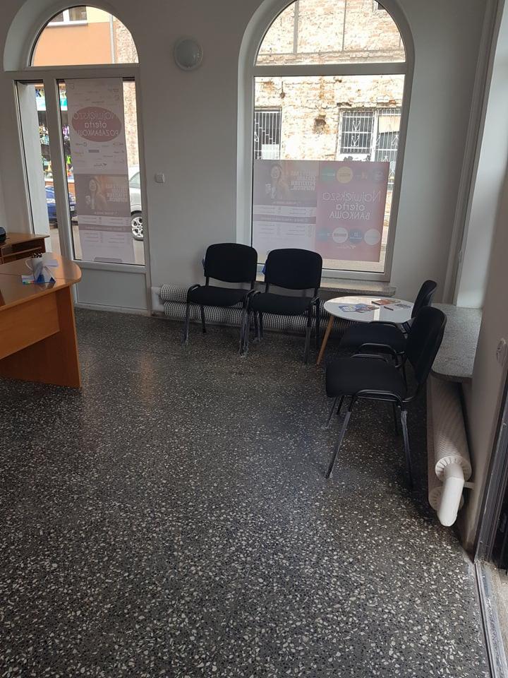 Poczekalnia z trzema krzesłami, stolikiem i plakatami w oknach, podłoga lastryko.