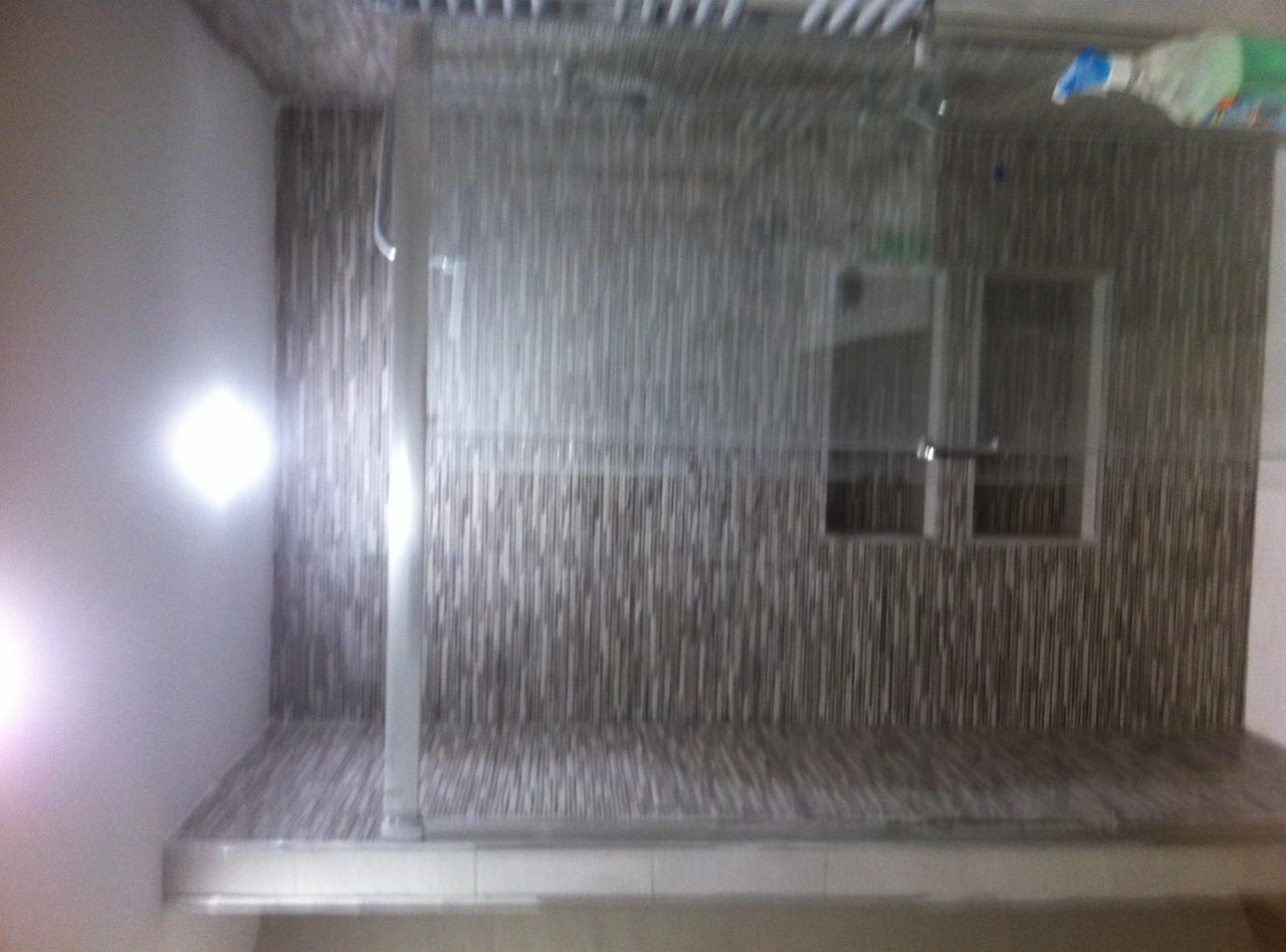 Wykończona kabina prysznicowa z deszczownicą, wyłożona mozaiką w odcieniach brązu i beżu, z widocznym oknem i półką wewnątrz.