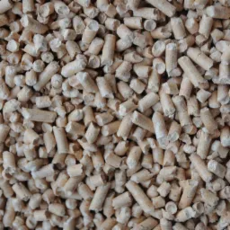 Jasne, cylindryczne granulki pelletu drzewnego, wypełniające kadr, z widoczną strukturą drewna i nieregularnymi krawędziami.