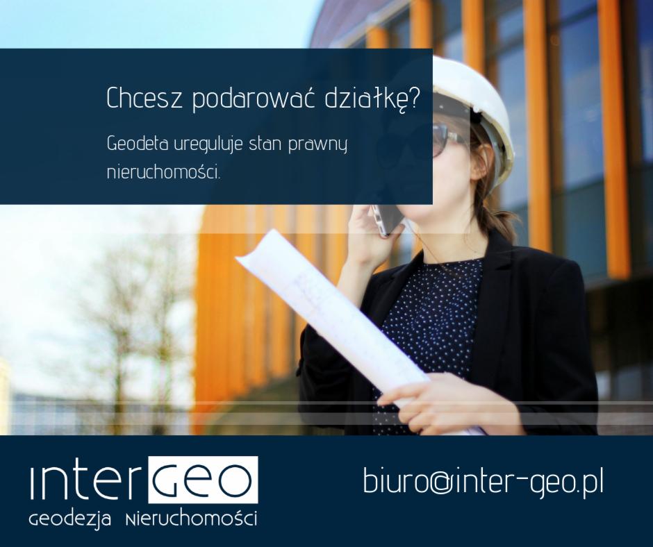 Geodetka w kasku rozmawia przez telefon trzymając zwinięte plany na tle nowoczesnego budynku z pomarańczowymi elementami fasady.