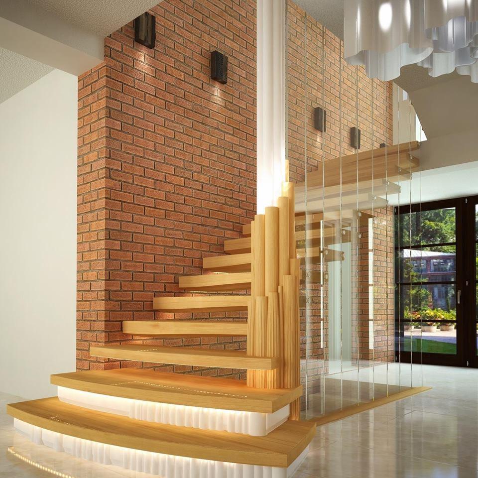Nowoczesne schody drewniane z podświetleniem LED na stopniach, wsparte na kolumnie z drewnianych prętów, z balustradą ze szkła, na tle ściany z cegły.