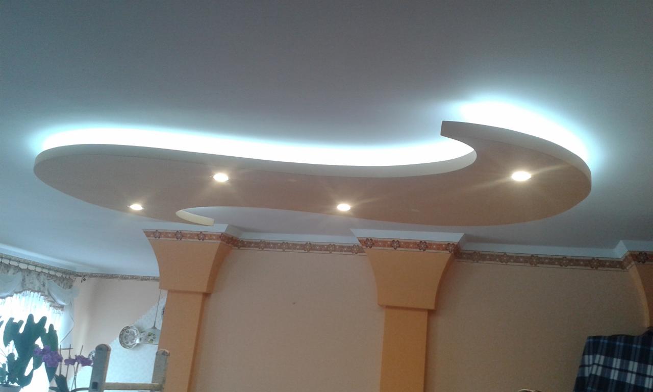 Sufit podwieszany z oświetleniem punktowym i listwą LED, dekoracyjne kolumny w pokoju z tapetą w kwiatowy wzór.