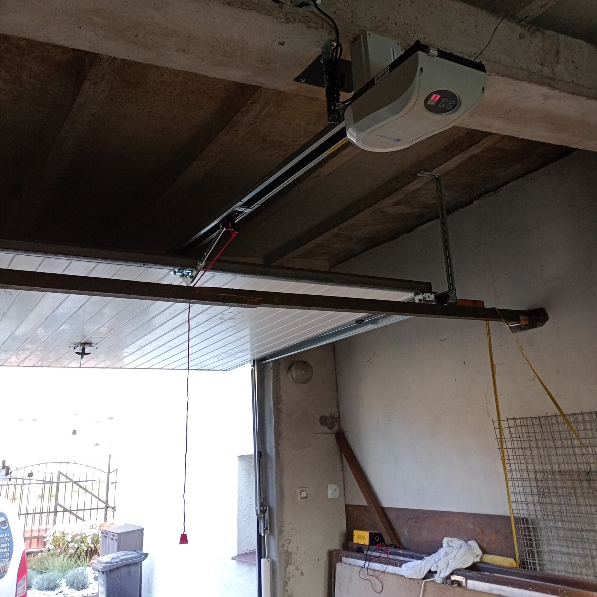 Zamontowany napęd bramy garażowej w Świdwinie. Widoczny mechanizm i brama w pozycji otwartej, z elementami konstrukcyjnymi.