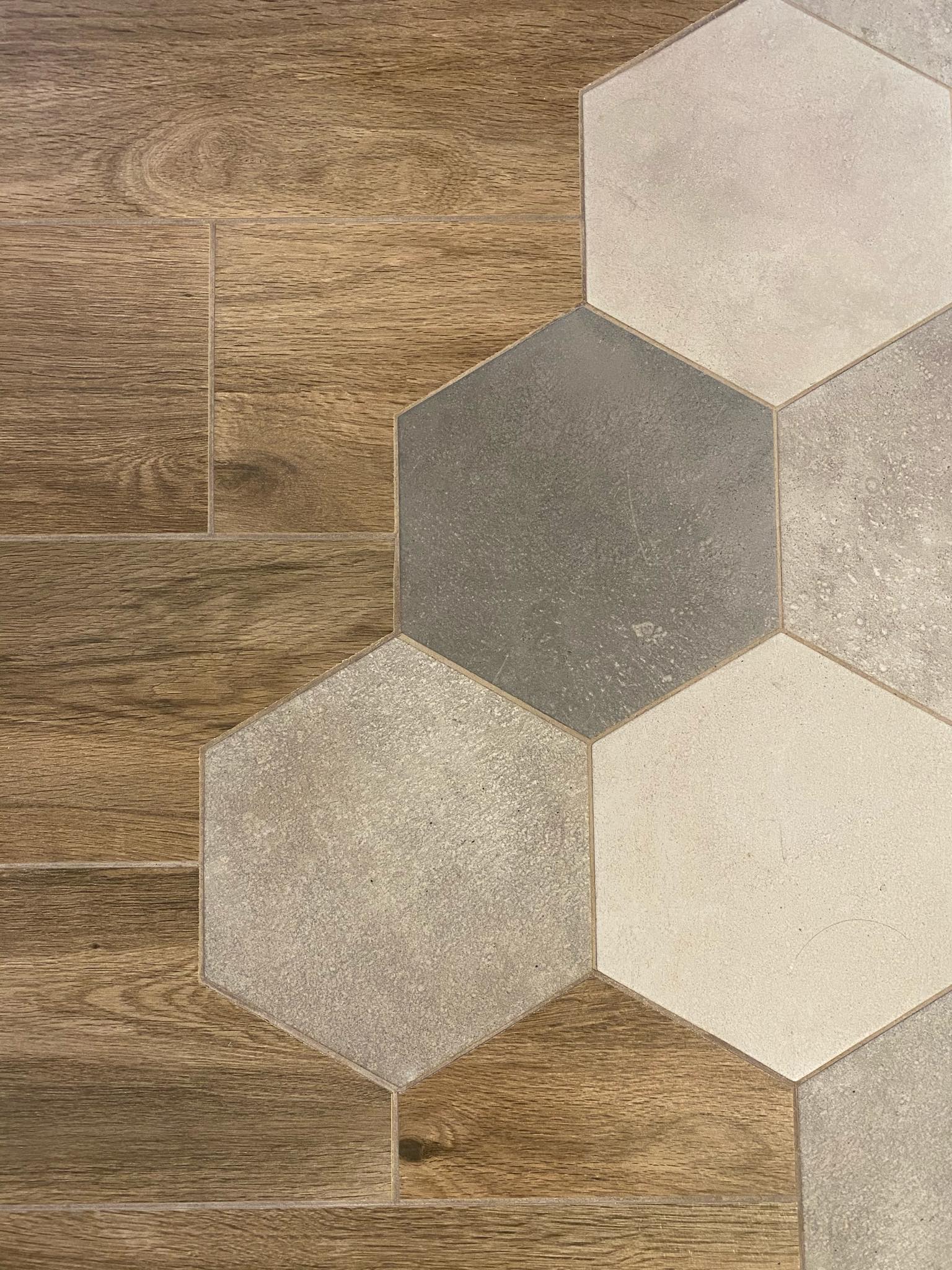 Połączenie drewnopodobnych płytek podłogowych w kształcie prostokątów z szarymi i beżowymi płytkami heksagonalnymi o zróżnicowanej fakturze.