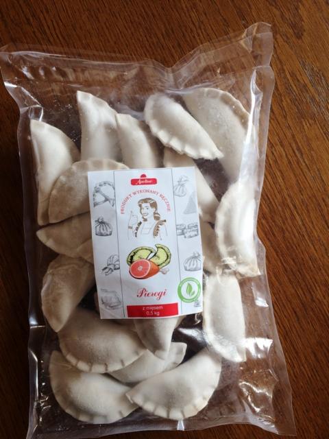 Mrożone pierogi z mięsem w przezroczystym opakowaniu foliowym, widoczna etykieta producenta z grafiką i napisem 'Pierogi z mięsem 0,5 kg'.