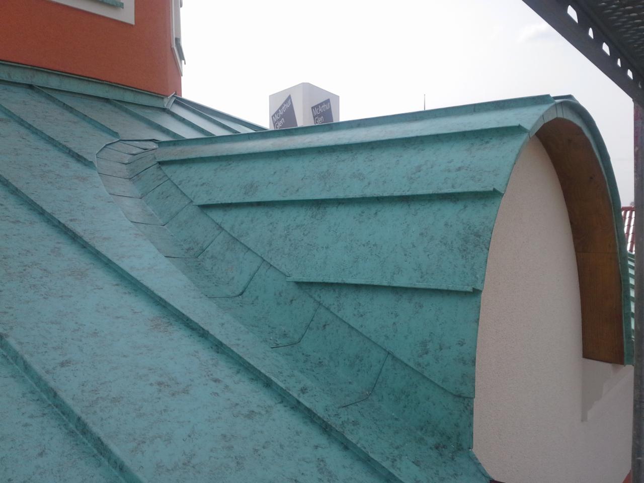 Nowe, miedziane pokrycie dachu z charakterystycznym patynowym wykończeniem, z detalami wykończeniowymi wokół lukarny dachowej.