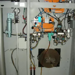 Kompleksowa instalacja przemysłowa z licznymi przewodami, zaworami, manometrami i filtrami, zamontowana na metalowej konstrukcji.