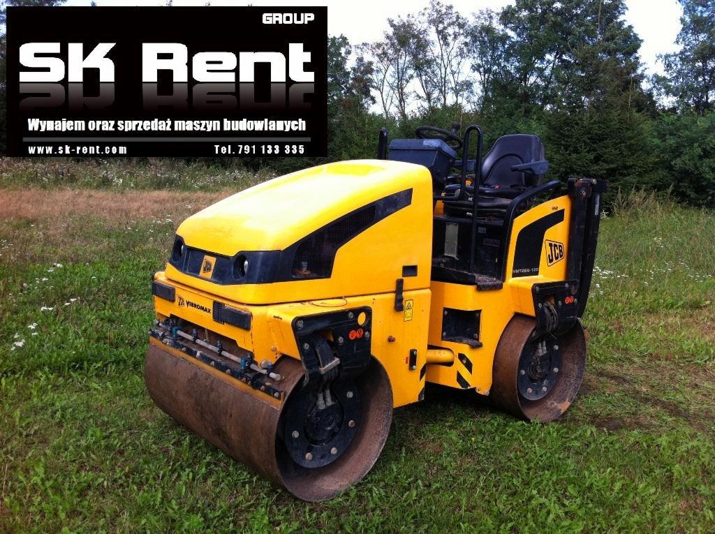 Żółty walec drogowy JCB Vibromax VMT260-120 stoi na trawie, w tle drzewa, widoczny logotyp SK Rent oferujący wynajem i sprzedaż maszyn budowlanych.