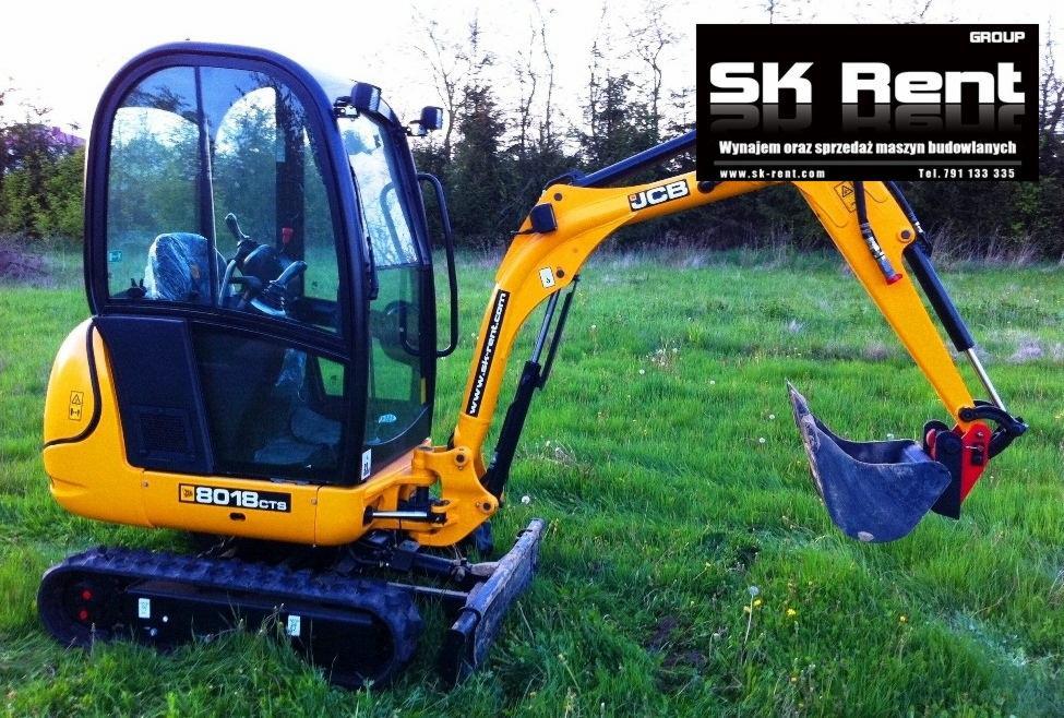 Żółta minikoparka JCB 8018CTS na gąsienicach, stojąca na trawiastym terenie, z widocznym logo firmy SK Rent w tle.