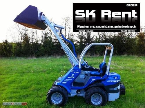 Niebieska, kompaktowa ładowarka kołowa marki Marim na zielonym trawniku, z logo firmy SK Rent w tle.