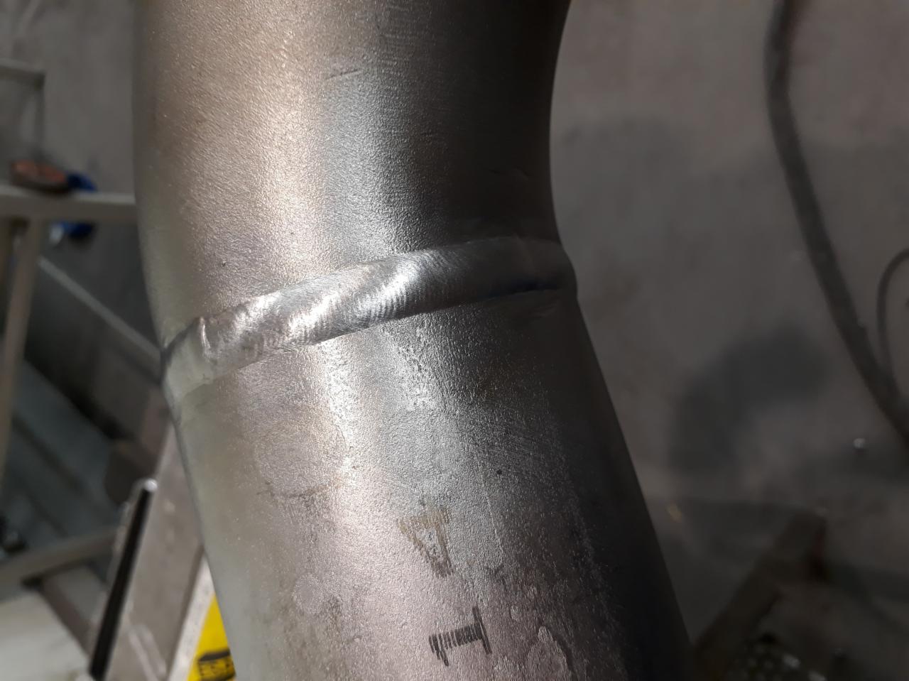 Spoina na metalowej rurze, widoczna linia złączenia, szlifowana powierzchnia, bliskie ujęcie.