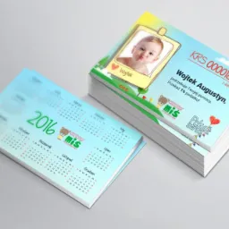Stos kalendarzy biurkowych z fotografią dziecka i informacją o przekazaniu 1% podatku na jego leczenie, z logo Przedszkole Meluzyna Integracyjne i Pokaz Serce