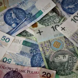 Stos banknotów polskich złotych o różnych nominałach (20, 50, 100), ułożonych warstwami, z widocznymi wizerunkami królów i godła Polski, z różnym oświetleniem i kątami nachylenia.